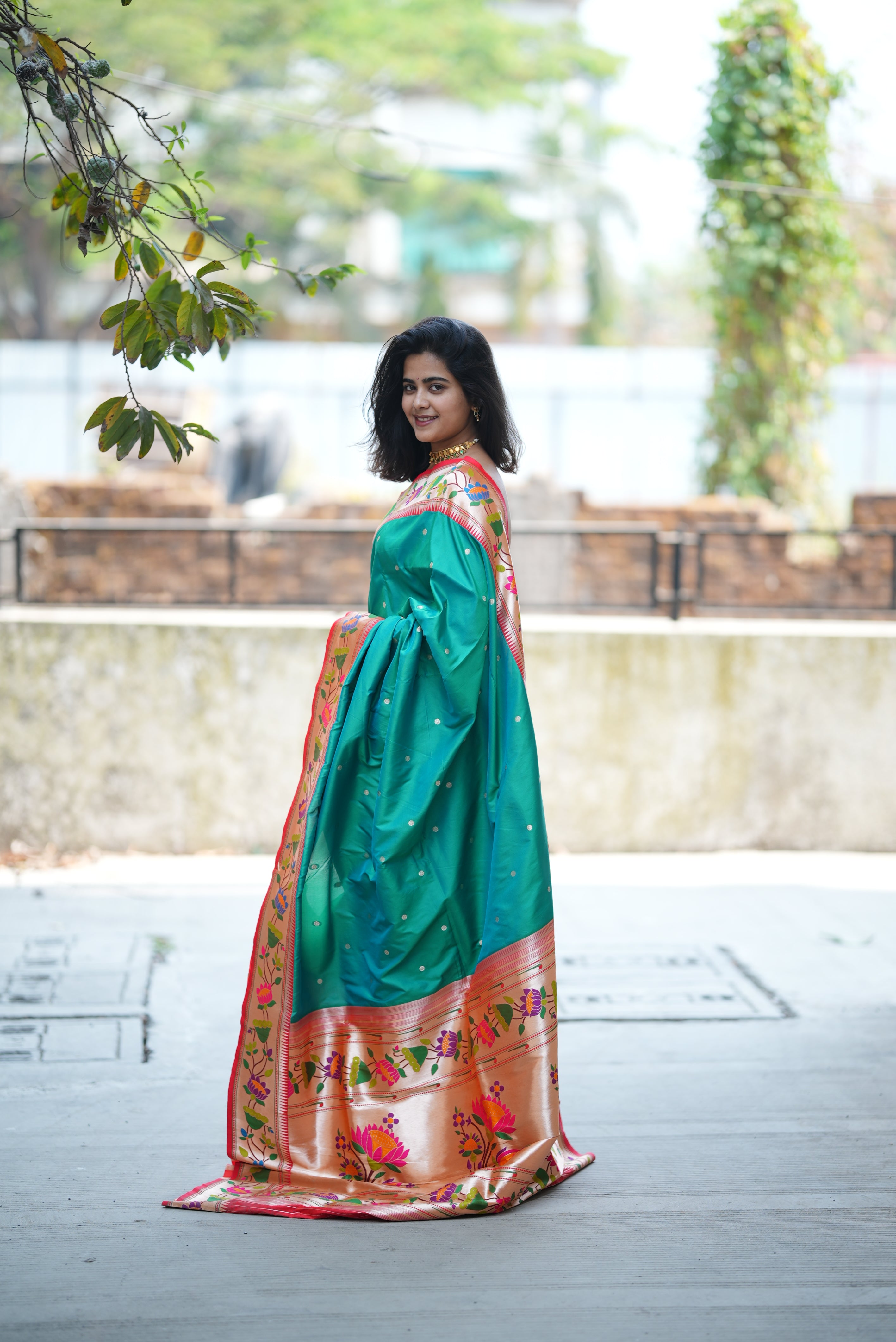 Teal green Paithani saree with a soft floral border and delicate zari buttas