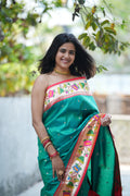 Teal green Paithani saree with a soft floral border and delicate zari buttas